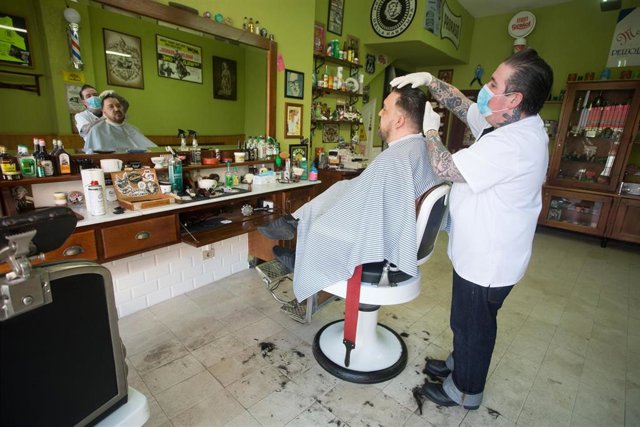 Un empleado de la peluquería Rockabilly ‘Memphis’, abierta durante el día 51 del estado de alarma, peina el pelo a un cliente