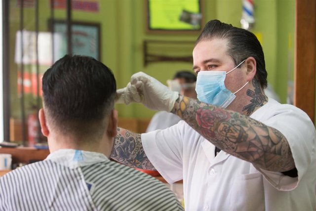 Un empleado de la peluquería Rockabilly ‘Memphis’, abierta durante el día 51 del estado de alarma, peina el pelo a un cliente. . En Lugo (Galicia, España) a 4 de mayo de 2020.