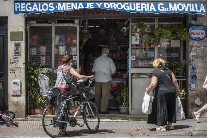 Varias personas guardan cola en una tienda.
