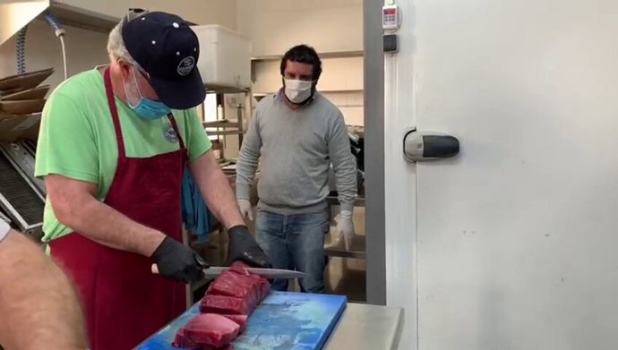 Uno de los voluntarios de los Servicios Sociales del Ayuntamiento de Tarifa manipulando los lomos de atún rojo