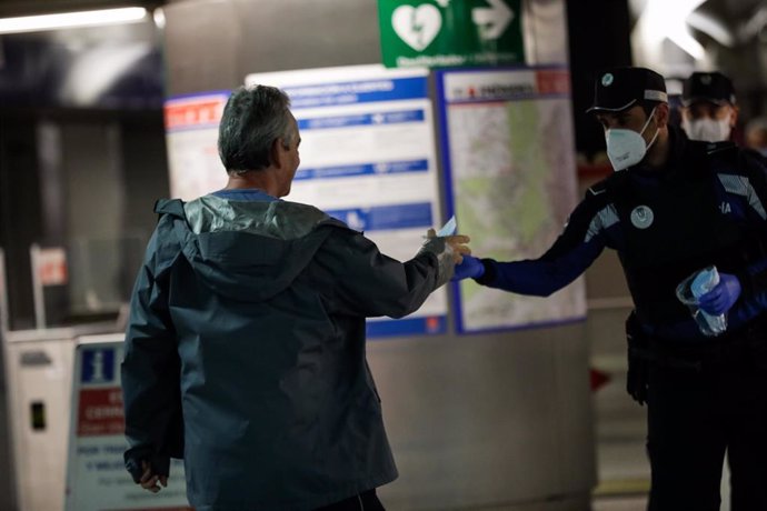 Agentes de la Policía Municipal de Madrid reparten mascarillas a los viajeros en la estación de metro de Sol 
