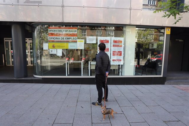 Un hombre pasa con su perro frente a una oficina de Empleo en la capital.