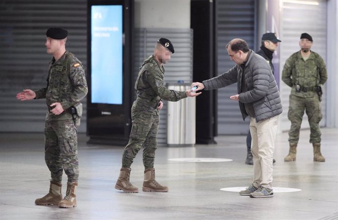 Un hombre le da gel desinfectante a uno de militares de la División Acorazada del Ejército que controlan la estación durante el cuarto día laborable del estado de alarma por la crisis del coronavirus en España, en Madrid (España), a 19 de marzo de 2020.