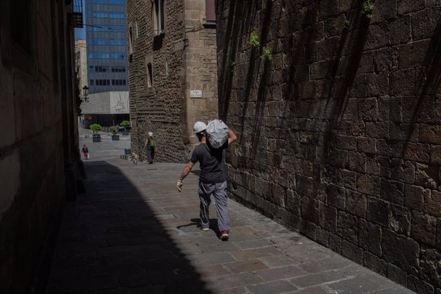 Un obrero camina con un saco al hombro durante el tercer día de desconfinamiento de adultos, en Barcelona/Catalunya (España) a 4 de mayo de 2020.