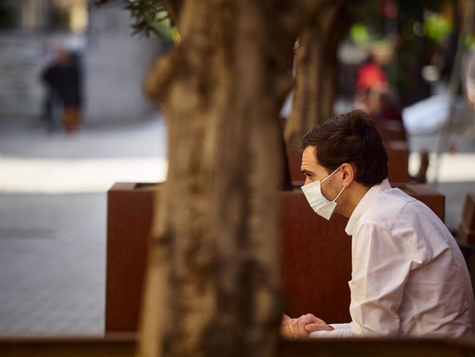 Un hombre con mascarilla descansa sentado en un banco durante el segundo día de la fase 0 de la desescalada en la que se permite la apertura con limitaciones de algunos establecimientos, en Pamplona/Navarra (España) a 5 de mayo de 2020.