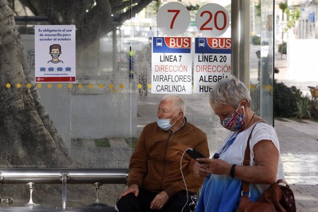 Dos personas esperan el autobús protegido con mascarilla, durante la fase 0 de la desescalada del Gobierno en el inicio de la semana 8 del estado de alarma decretado por el coronavirus. En Málaga(Andalucía, España), a 04 de mayo de 2020.