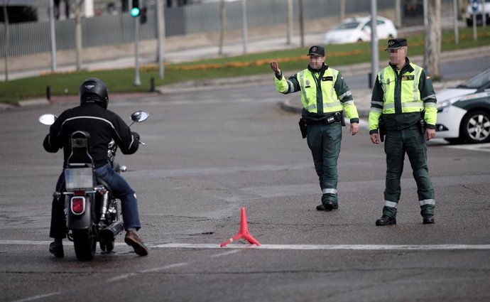 Dos guardias civiles de Tráfico paran a una moto que se encuentra cerca de la entrada del recinto de IFEMA (Madrid) durante la vigencia del Estado de Alarma