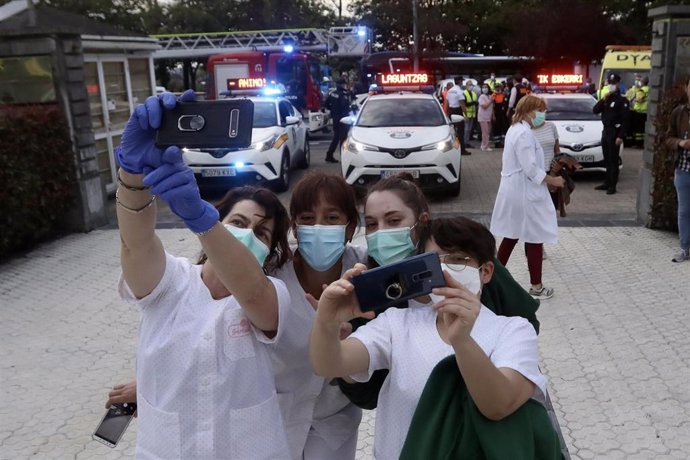 Varias sanitarias con mascarilla se hacen un selfie tras el aplauso en el Hospital Donostia junto a trabajadores.