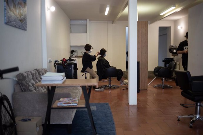 Un peluquero atiende a un cliente durante la fase 0 de la desescalada donde algunos comercios han abierto con medidas restrictivas y de seguridad con el fin de evitar nuevos contagios. En Barcelona, Cataluña, (España), a 5 de mayo de 2020.