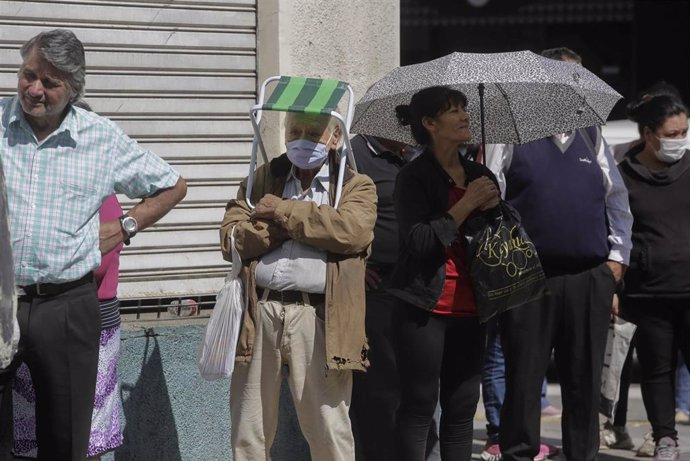 Personas hacen cola para poder acceder a una entidad bancaria en San Miguel de Tucumán, en el norte de Argentina, días después de que el Gobierno decretara la cuarentena para hacer frente al avance de la pandemia de Covid-19.
