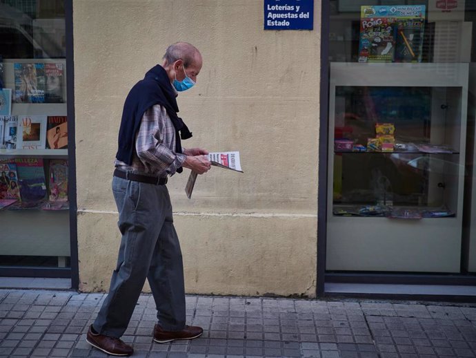 Un hombre camina con mascarilla leyendo un periódico durante el segundo día de la fase 0 de la desescalada y durante el periodo en el que la salida de mayores de 70 años se establece de 10 a 12 horas y de 19 a 20 horas, en Pamplona/Navarra (España) a 5 