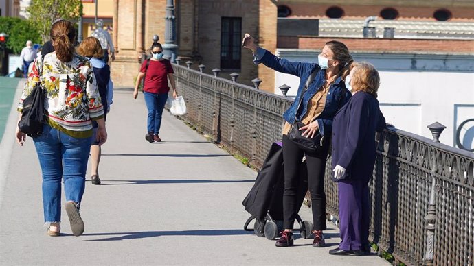 Personas mayor protegido con mascarilla pasea por el puente de Triana, foto de archivo