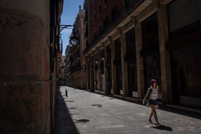 Una mujer pasea por una calle durante el tercer día de desconfinamiento de adultos y durante la fase 0 de la desescalada en la que se permite la apertura de ciertos establecimientos, en Barcelona/Catalunya (España) a 4 de mayo de 2020.
