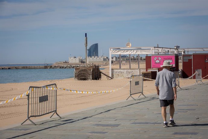 Un hombre pasa junto a la base náutica de la playa del Bogatell. En Barcelona (España), a 7 de mayo de 2020.
