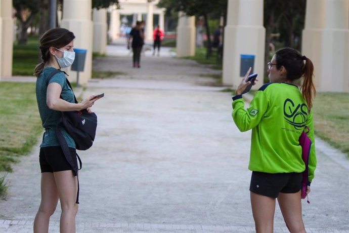 Dos jóvenes mantienen una conversación preservando la distancia de seguridad mientras pasean 