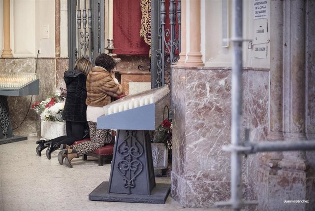 Dos fieles oran en la parroquia de San Pablo de Málaga capital, sede canónica de la Cofradía del Cautivo y la Trinidad