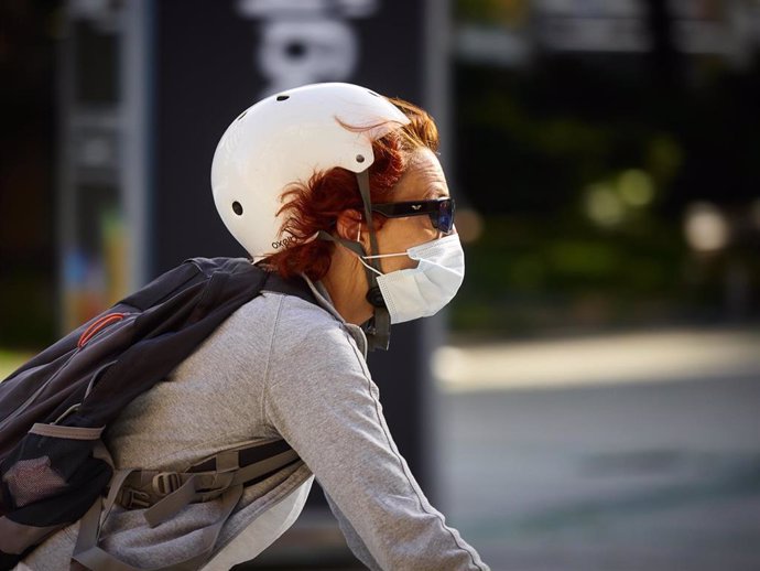 Una mujer con mascarilla para protegerse del coronavirus monta en bicicleta