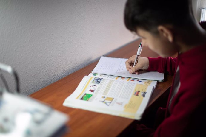 Un niño realiza sus deberes en su habitación durante el confinamiento