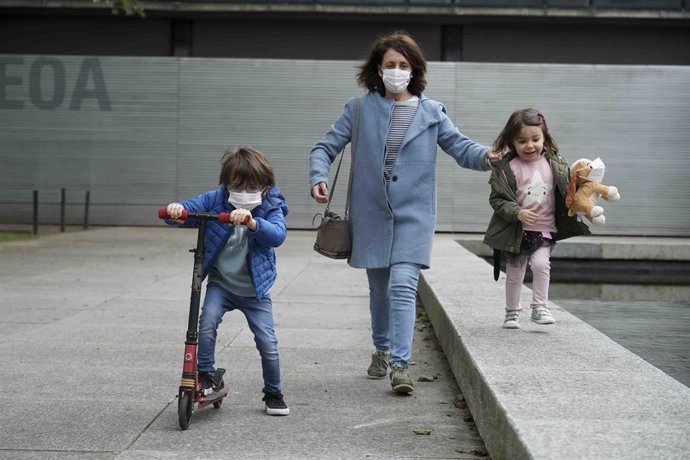 Una mujer pasea junto a una niña y un niño en las calles de Bilbao.