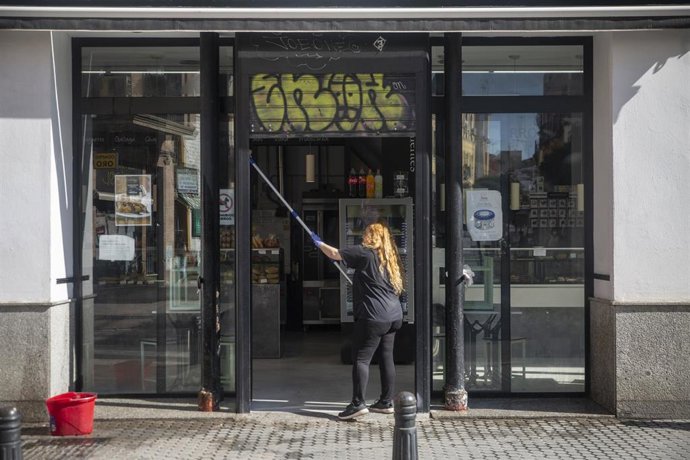 Una trabajadora limpia la fachada de una cafetería. En Sevilla, (Andalucía,España), a 08 de mayo de 2020.
