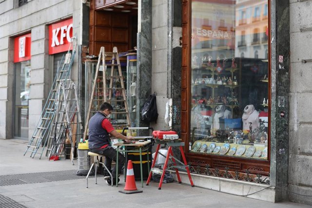 Un hombre protegido con mascarilla trabaja en la puerta de su ferretería durante el tercer día desde que se decretó el estado de alarma en el que se permite la apertura con limitaciones de pequeños comercios.