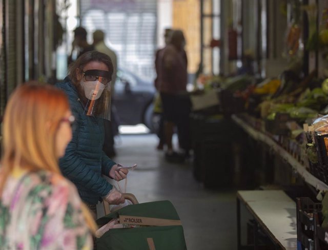 Una mujer protegida con mascarilla y pantalla protectora guarda turno en una frutería, durante el día 46 del estado de por la pandemia del coronavirus, (Covid-19). En Sevilla (Andalucía, España), a 29 de abril de 2020.