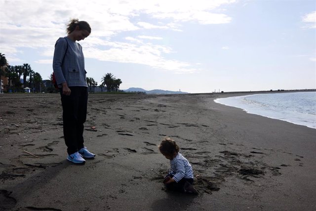 Una mujer con su hijo en la playa de La Malagueta el primer día en el que los menores de 14 años pueden salir, en Málaga (Andalucía ,España) a 26 de abril de 2020.