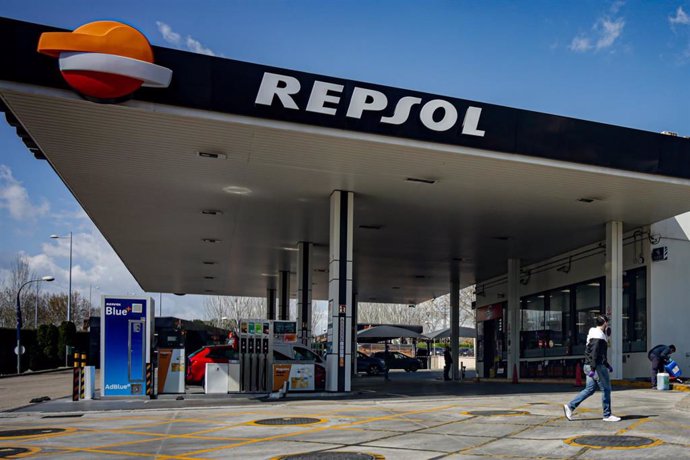 Un joven protegido con mascarilla pasa al lado de una gasolinera de Repsol ubicada en Madrid abierta