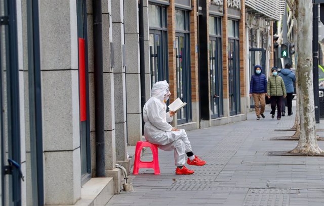 Una perosna lee en una calle de Wuhan durante la pandemia.