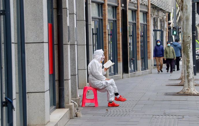 Una perosna lee en una calle de Wuhan durante la pandemia.