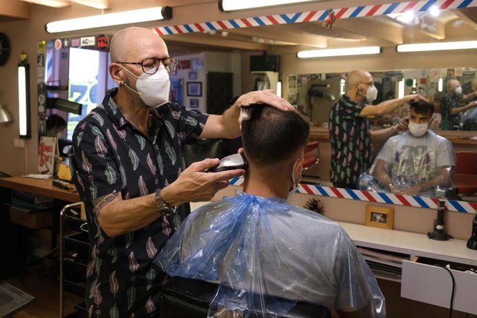 Un peluquero pasa la maquinilla de afeitar a un cliente en Palma este lunes.