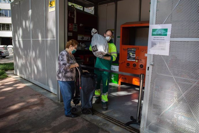 Una mujer lleva una bolsa a uno de los puntos verdes de Barcelona que han abierto hoy tras la reincorporación de 1.000 operarios de limpieza del servicio municipal durante la fase 0 de la desescalada en la ciudad