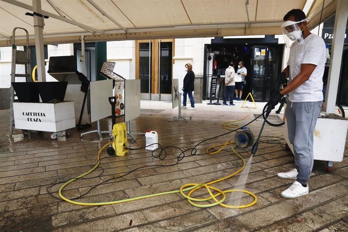 Un trabajador de la cafetería La Plaza, ubicada en la Plaza de La Marina, desinfecta el mobiliario de dicha cafetería para la apertura  en la Fase 1. Málaga a 7 de mayo del 2020