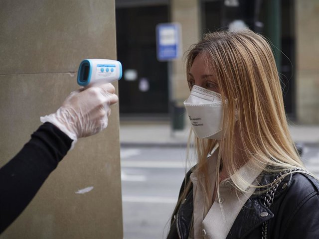 Una trabajadora de la tienda de moda Urban Sons le toma la temperatura a una clienta