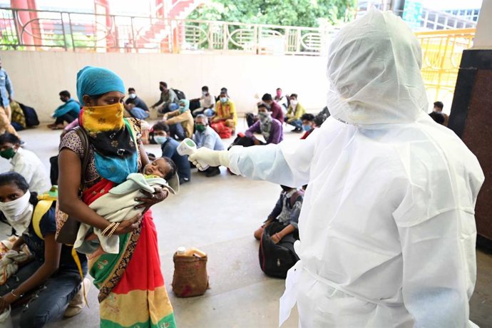 Imagen de archivo de un trabajador tomando la temperatura a varias personas  