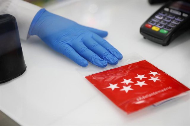 Una farmacéutica entrega una mascarilla FFP2 que reparte la Comunidad de Madrid.