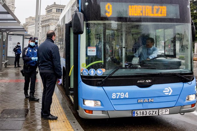 Un agente de la Policía Municipal de Madrid reparte mascarillas a los pasajeros de un autobús de la línea 9 de la EMT de Madrid.