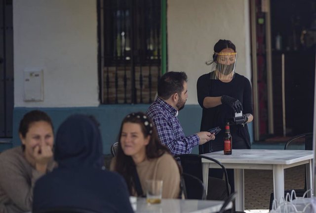 Una camarera atiende la terraza de un bar, el día en el Sevilla pasa a la fase 1 del plan de desescalada que ha elaborado el Gobierno de España. En esta fase, las terrazas de los restaurantes y establecimientos del sector de la hostelería, pueden estar ab