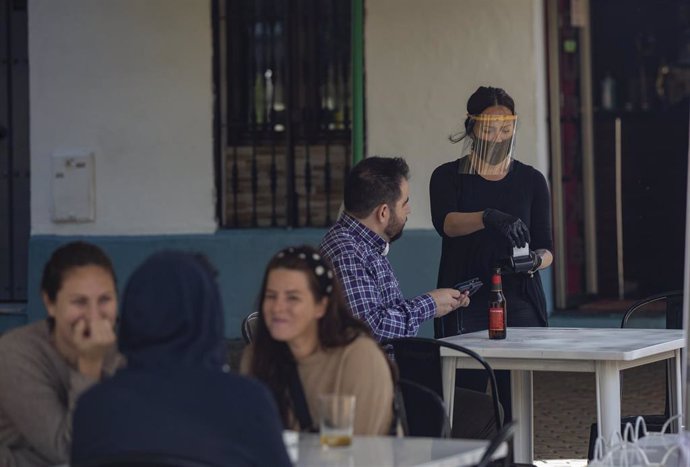Una camarera atiende la terraza de un bar, el día en el Sevilla pasa a la fase 1 del plan de desescalada que ha elaborado el Gobierno de España. En esta fase, las terrazas de los restaurantes y establecimientos del sector de la hostelería, pueden estar 