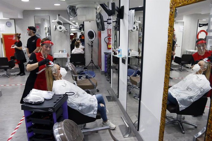 Una peluquera tiñe el pelo a una clienta durante el día 51 del estado de alarma, donde peluquerías y los salones de belleza abren por primera vez desde el estado de alarma el lunes 4 de mayo. En Málaga (Andalucía, España),04 de mayo de 2020.