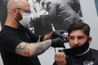 Un peluquero cortando al pelo a un cliente en una peluquería de Florida