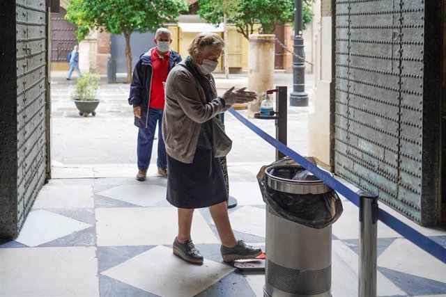 Una ciudadana se lava las manos con un gel colocado en la puerta de  la Catedral de Sevilla el primer día de la fase 1 por la pandemia del coronavirus. Sevilla a 11 de mayo del 2020