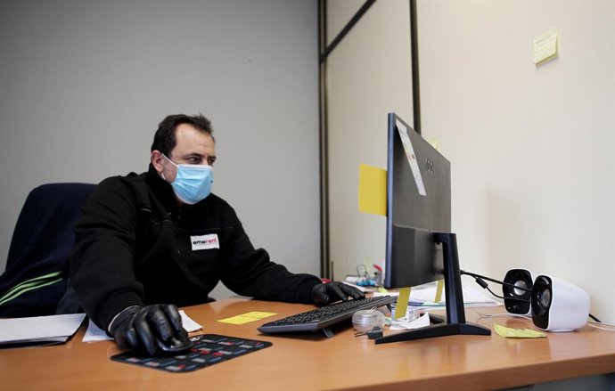 Un operari protegit amb una mascarilla i guants treballa des de l'ordinador, a Madrid (Espanya), a 14 d'abril de 2020.