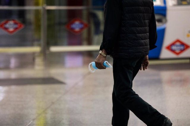 Un viajero porta una mascarilla en una mano en la estación de metro de Sol