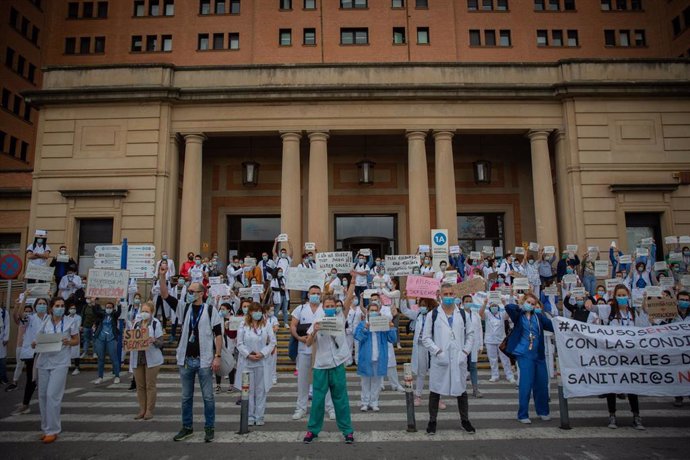 Decenas de miembros del personal sanitario protegidos con mascarilla sostienen carteles durante la concentración de sanitarios en el Día Internacional de la Enfermería a las puertas del Hospital Vall d'Hebron, en Barcelona (Catalunya, España), a 12 de m