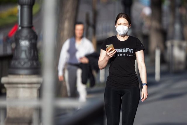 Una mujer con mascarilla hace una foto con el móvil en el segundo día de desconfinamiento durante la Pandemia Covid-19 que ha generado el Estado de Alarma en España. A 3 de Mayo, 2020 en Madrid, España