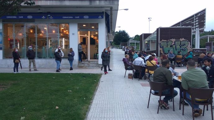 Gente hace cola para sentarse en una terraza hostelera en Gijón el primer día permitido tras el Estado de Alarma