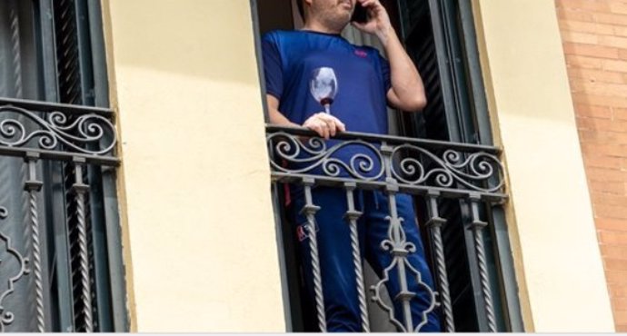 Un hombre en el balcón de su casa con una copa de vino