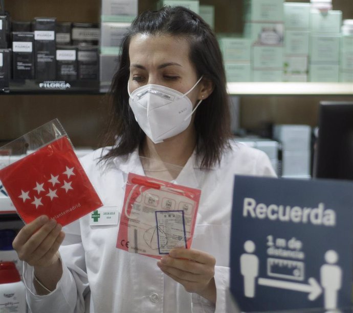 Una farmacéutica muestra una mascarilla en la Farmacia CEA, una de las 2.882 farmacias madrileñas 