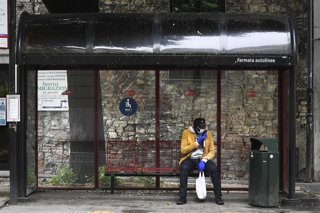 Un hombre con mascarilla espera un autobús en Italia